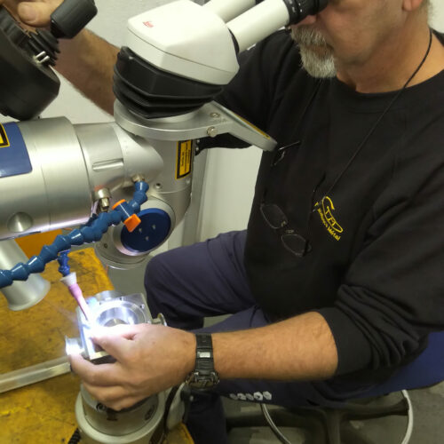 Salarié de l'entreprise CTM laser en train d'effectuer une opération de rechargement par laser sur une pièce.